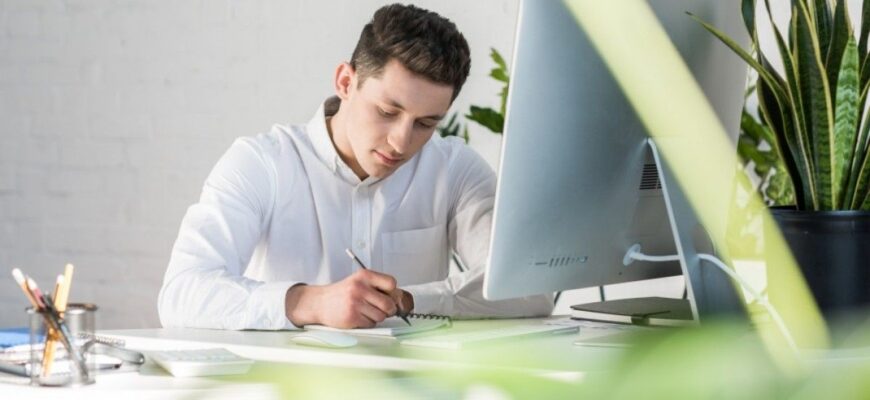 Фото мужчина на рабочем месте делает записи